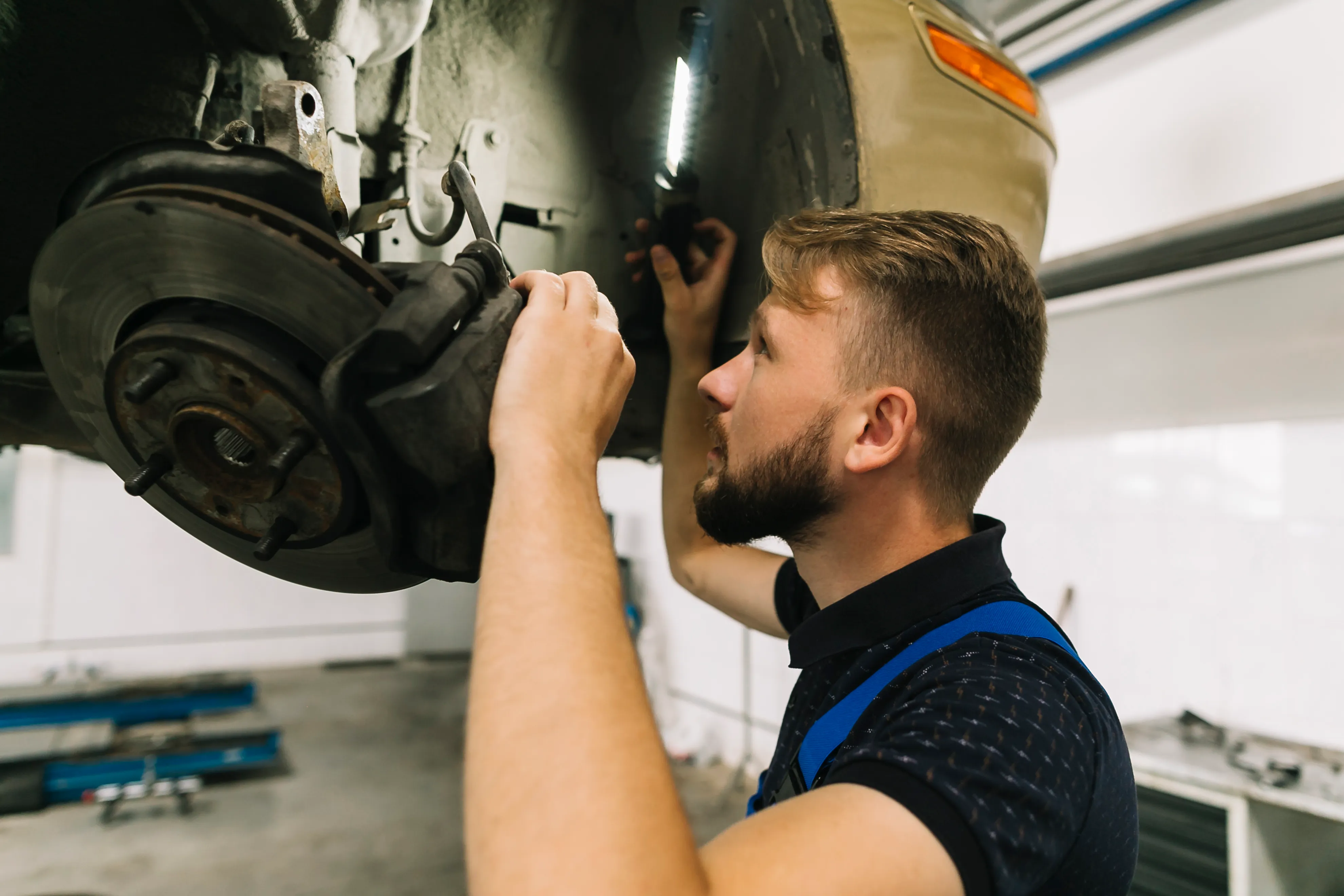 Symbolfoto: Mechaniker prüft die Bremsanlage am angehobenen Fahrzeug